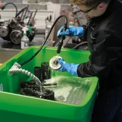 Técnico limpando peças metálicas em cuba de limpeza industrial